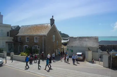 a group of people walking down a street in front of a building at Meledor in Marazion
