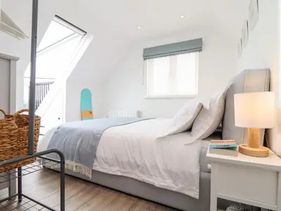 a white bedroom with a bed and a window at Marazion Attic in Marazion