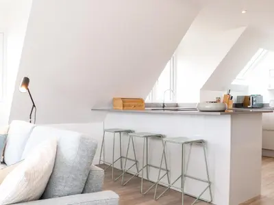 a living room with a couch and a kitchen at Marazion Attic in Marazion