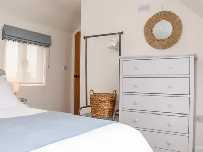 a bedroom with a bed and a dresser and a mirror at Marazion Attic in Marazion