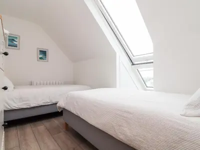 two beds in a white bedroom with a skylight at Marazion Attic in Marazion