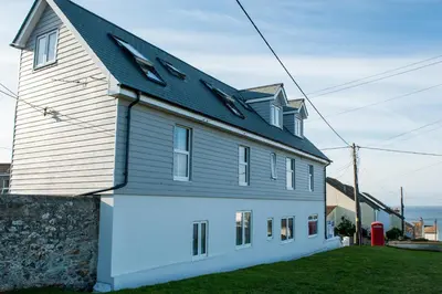 a white house with a black roof at Marazion Attic in Marazion