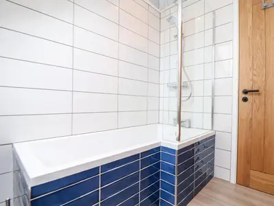 a bathroom with blue and white tiles and a tub at Marazion Attic in Marazion