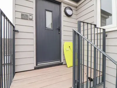 a yellow suitcase sitting on a porch next to a door at Marazion Attic in Marazion