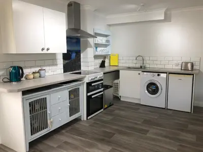 a kitchen with white cabinets and a washer and dryer at Little Valley View in Otterham