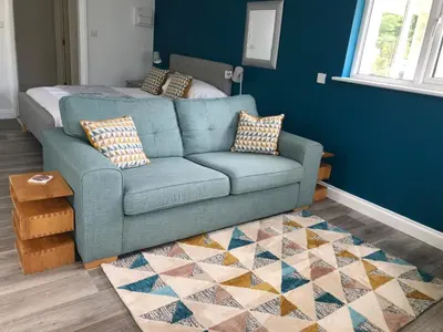 a blue couch in a living room with a rug at Little Valley View in Otterham