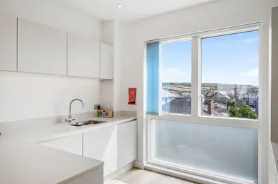 a kitchen with white cabinets and a large window at 5 The Dunes in Perranporth