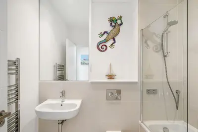 a white bathroom with a sink and a shower at 5 The Dunes in Perranporth