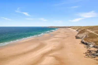 a sandy beach with the ocean on a sunny day at 5 The Dunes in Perranporth