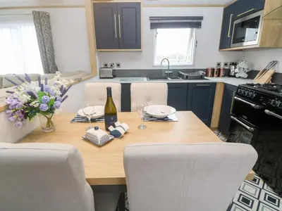 a kitchen with a wooden table with a bottle of wine at Chantry Lodge in Newquay