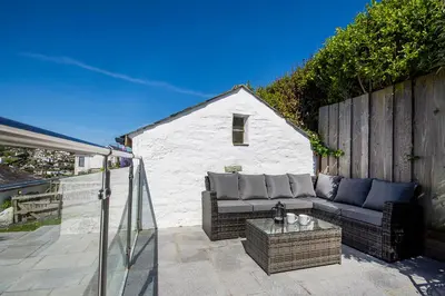a patio with a couch and a table at Coastguard Cottage Cornwall - Sea & Harbour Views in Mevagissey
