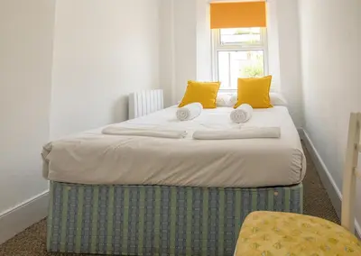 a bedroom with a large bed with yellow pillows at Coastguard Cottage Cornwall - Sea & Harbour Views in Mevagissey