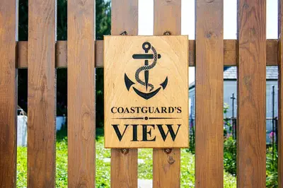 a wooden sign on a wooden fence at Coastguard Cottage Cornwall - Sea & Harbour Views in Mevagissey