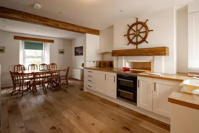 a kitchen with a table and a dining room at Coastguard Cottage Cornwall - Sea & Harbour Views in Mevagissey