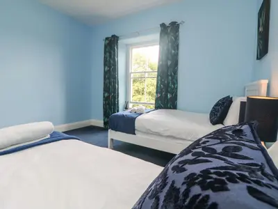 a bedroom with two beds and a window at Gweek House in Helston