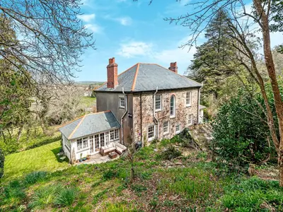 an old brick house in the middle of a field at Gweek House in Helston