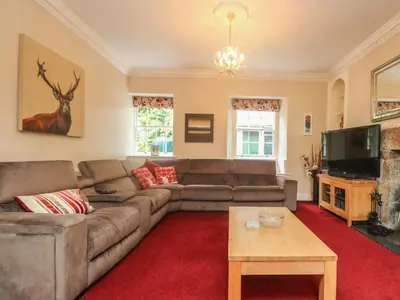 a living room with a couch and a tv at Gweek House in Helston