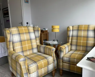 two chairs and a table with a lamp in a room at Sirens Sunset Peaceful Retreat with stunning sea views, 5 minutes from Porth Beach in Newquay