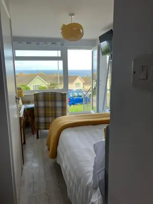 a bedroom with a bed and a view of the ocean at Sirens Sunset Peaceful Retreat with stunning sea views, 5 minutes from Porth Beach in Newquay