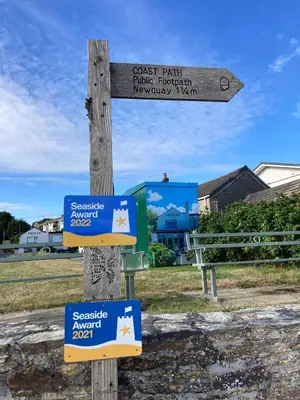 a wooden sign with two signs on a pole at Sirens Sunset Peaceful Retreat with stunning sea views, 5 minutes from Porth Beach in Newquay