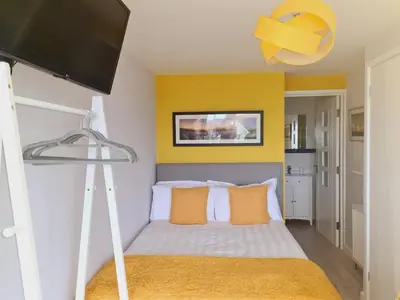 a bedroom with a bed with a yellow wall at Sirens Sunset Peaceful Retreat with stunning sea views, 5 minutes from Porth Beach in Newquay