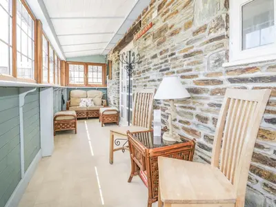 a living room with chairs and a stone wall at Dovecote in Saint Goran