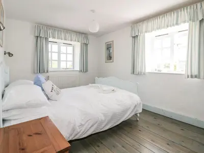 a bedroom with a white bed and two windows at Owls Roost in Saint Goran