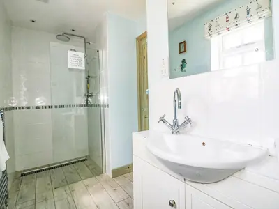 a white bathroom with a sink and a shower at Squirrels Dray in Saint Goran