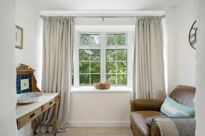 a living room with a window and a chair at Jade Cottage in St. Agnes