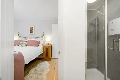 a bedroom with a bed and a glass shower at Jade Cottage in St. Agnes