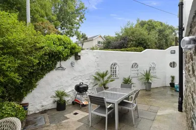 a patio with a table and chairs and a grill at Jade Cottage in St. Agnes