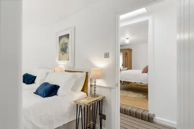a white bedroom with a bed and a mirror at Jade Cottage in St. Agnes