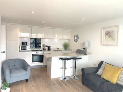 a kitchen with a counter and a chair and a couch at Ocean Gate in Newquay