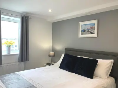 a bedroom with a white bed with a window at Ocean Gate in Newquay