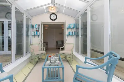 a room with chairs and a table and a clock at Ocean Gem in Carbis Bay