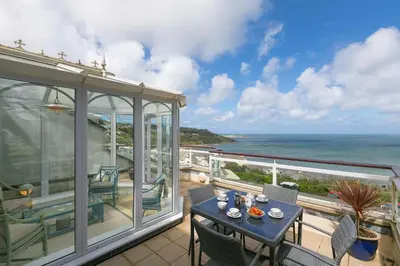 a balcony with a table and chairs and the ocean at Ocean Gem in Carbis Bay