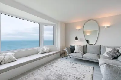 a living room with a couch and a large window at Golden Heights in Carbis Bay