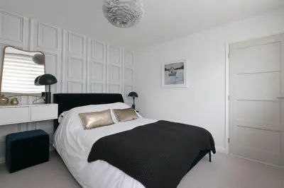 a bedroom with a bed with a black blanket and a mirror at Golden Heights in Carbis Bay
