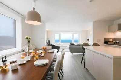 a kitchen and living room with a wooden table in a room at Golden Heights in Carbis Bay