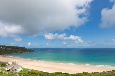 a beach with a house and the ocean at Golden Heights in Carbis Bay
