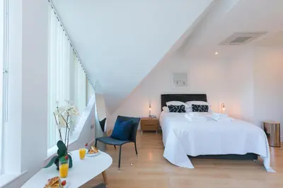 a bedroom with a bed and a chair in a attic at Ithaca in St Ives