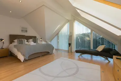 a bedroom with a bed and a large window at Ithaca in St Ives