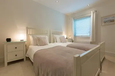 a white bedroom with two beds and a window at Coast in St Ives