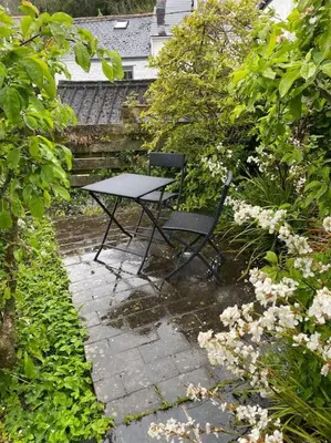 a table and a chair sitting on a stone patio at Fuchsia Cottage in Flushing