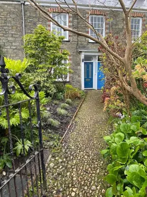 a pathway leading to a house with a blue door at Fuchsia Cottage in Flushing