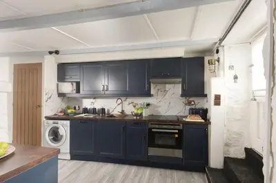 a kitchen with blue cabinets and a washer and dryer at Mariners Cottage, St Ives in St Ives