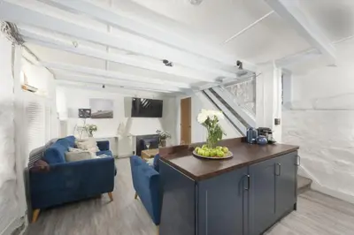 a living room with a blue couch and a table at Mariners Cottage, St Ives in St Ives