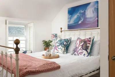 a bedroom with a bed with pillows and a painting at Mariners Cottage, St Ives in St Ives