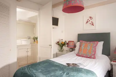a bedroom with a bed with a green blanket at Mariners Cottage, St Ives in St Ives
