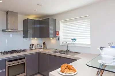 a kitchen with stainless steel appliances and a glass table at Carbis Sands in Carbis Bay